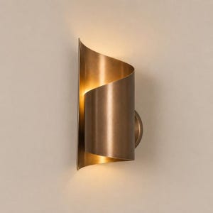 Könnte beinhalten: Eine Wandleuchte mit einem geschwungenen, bronzefarbenen Metallschirm. Das Design besteht aus zwei überlappenden, rollenförmigen Metallpaneelen, die ein warmes, diffuses Licht erzeugen, das aus den oberen und unteren Öffnungen der Leuchte austritt.