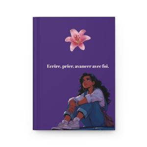 May include: Purple journal with an illustration of a woman looking up, a pink lily, and the French text "Ecrire, prier, avancer avec foi." The woman is wearing a white shirt, blue overalls, and sneakers. The journal cover is a solid purple.