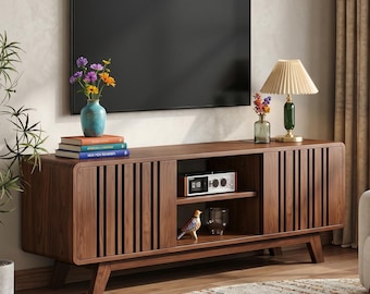 Mueble para TV de estilo moderno de mediados de siglo en nogal con puertas corredizas y consola multimedia con espacio de almacenamiento.