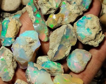 May include: A collection of raw, unpolished opal stones featuring a milky white base with vibrant flashes of neon green, blue, and orange fire. These irregular, rough-textured mineral specimens display natural inclusions and varied shapes.