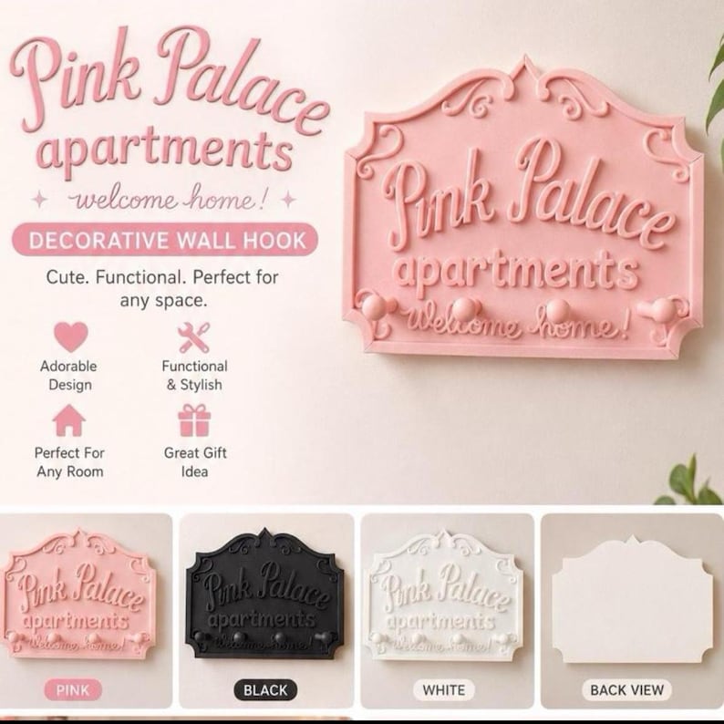 Może przedstawiać: R&oacute;żowy dekoracyjny wieszak ścienny z napisami "Pink Palace apartments" i "welcome home!" w kursywie. Wieszak ma trzy małe gałki do wieszania przedmiot&oacute;w. Dodatkowe wieszaki pokazano w kolorze czarnym i białym.