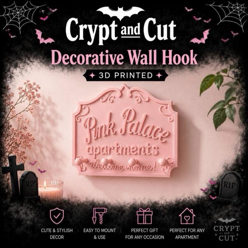 Może przedstawiać: R&oacute;żowy, drukowany w 3D dekoracyjny wieszak ścienny z napisem "Pink Palace apartments welcome home!". Wieszak ma dekoracyjną obw&oacute;dkę i jest zaprojektowany w stylu Halloween. Obraz zawiera r&oacute;wnież nietoperze, nagrobki i tekst "Crypt and Cut".