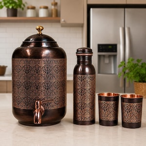 May include: A dark copper-toned water dispenser with a lid and spigot, a matching water bottle, and two tumblers. Each item features a dark, brushed finish with an intricate, repeating floral pattern in a lighter copper color across the center.