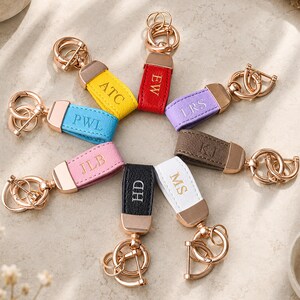 Puede incluir: Un conjunto de ocho llaveros de cuero en amarillo, rojo, morado, azul, rosa, negro, blanco y marrón. Cada llavero cuenta con un cierre de metal en oro rosa y una trabilla con iniciales grabadas: ATC, EW, LRS, PWL, JLB, HD, MS y KJ.