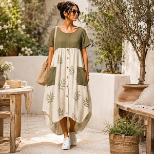 May include: A midi-length dress featuring an olive green bodice and a cream-colored skirt with a green leaf print. The dress has short sleeves, a round neckline, a front button placket, and two large patch pockets on the sides of the skirt.