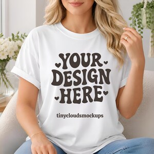 Könnte beinhalten: Weißes T-Shirt mit dem Text "YOUR DESIGN HERE" in brauner Retro-Schriftart, umgeben von kleinen Herzen. Darunter steht "tinycloudsmockups". Ein klassisches, lässiges Kleidungsstück.