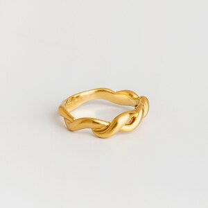 May include: A gold-toned ring with a twisted, wave-like design.