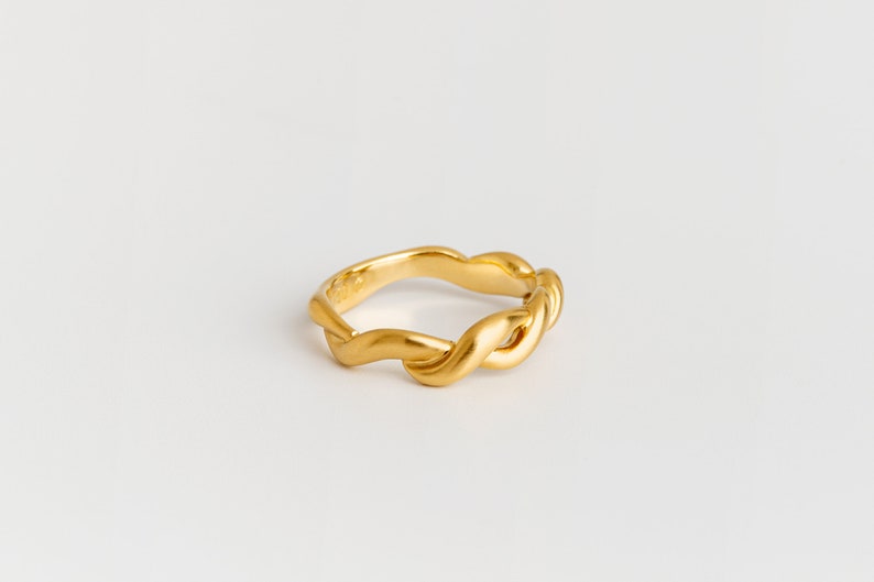 May include: A gold-toned ring with a twisted, wave-like design.