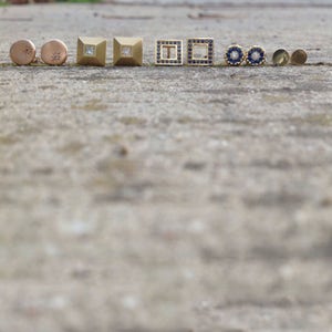 May include: A collection of nine gold earrings with various designs. Some earrings feature small diamonds, while others have blue gemstones.
