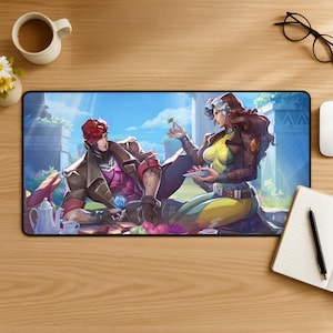 May include: A rectangular desk mat featuring a colorful illustration of two characters having a picnic. One character has red hair and a brown jacket, while the other has long brown hair, a yellow bodysuit, and a brown jacket. They are surrounded by fruit.