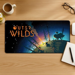 Könnte beinhalten: Eine rechteckige Schreibtischunterlage mit dem Outer Wilds-Logo in orangefarbenem Text auf der linken Seite. Die Grafik zeigt eine dunkle, sternenklare Nachtszene mit einem Lagerfeuer, hohen silhouettierten Bäumen und einem Raumschiff.