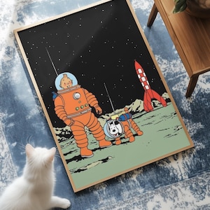 May include: Framed print featuring a cartoon illustration of a spaceman and a dog on a planet with a red and white rocket. The spaceman and dog are wearing orange space suits. The background is black with stars.