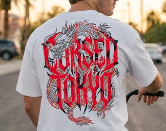 May include: A white short-sleeve t-shirt featuring a large graphic on the back. The design displays a red and black dragon intertwined with bold, stylized red lettering that reads "CURSED TOKYO" in a sharp, angular font style.