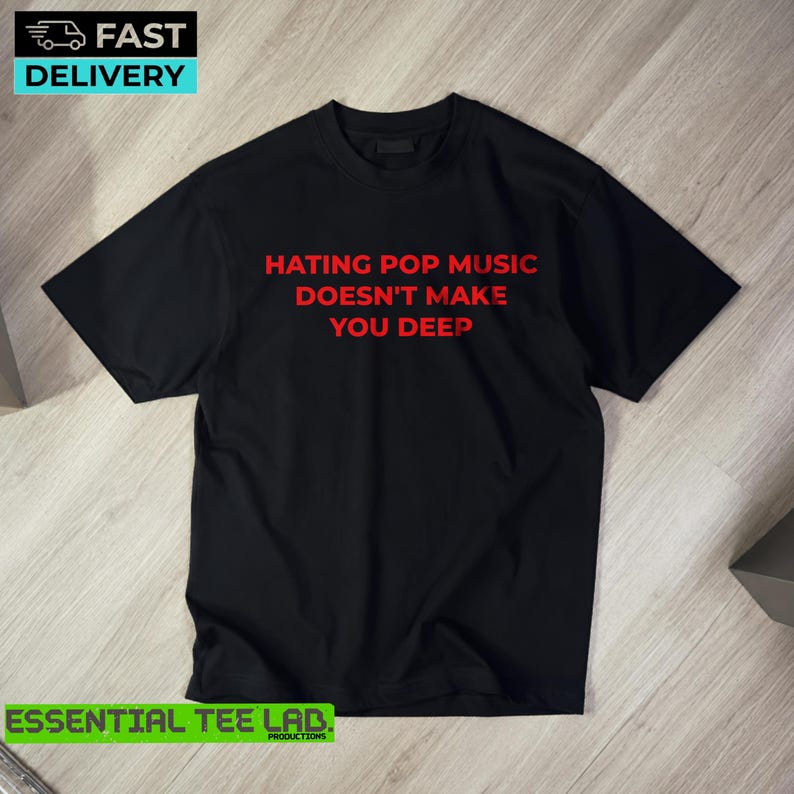 May include: A black short-sleeved t-shirt featuring the red text "HATING POP MUSIC DOESN'T MAKE YOU DEEP" printed in a bold, sans-serif font across the center of the chest. The garment has a classic crew neckline and a straight hem.