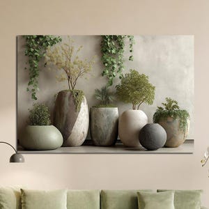 Peut inclure: Une impression sur toile représentant une collection de plantes en pot contre un mur neutre. Les pots varient en forme et en couleur, avec un feuillage vert. La scène est située au-dessus d'un canapé vert avec des coussins assortis.