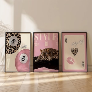 May include: Three framed wall art prints. The left print shows two eight balls, one with a leopard print and one pink, with the word lucky. The center print features a leopard on a pink background with the text STYLE. The right print shows an ace of hearts card with a leopard print heart and a pink lip print.