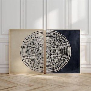 May include: Two square framed wall art pieces featuring circular patterns of dots. The left piece displays black dots on a beige background, while the right piece shows beige dots on a dark navy blue background. Both prints are encased in thin gold frames.