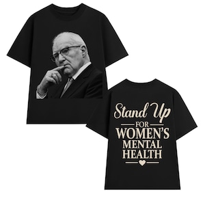 May include: A black short-sleeved t-shirt featuring a black and white photographic print of an older person in a suit and glasses on the front, and the text "Stand Up FOR WOMEN'S MENTAL HEALTH" with a small heart icon printed on the back.