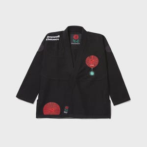 Puede incluir: Una chaqueta de kimono para artes marciales de color negro con el texto "Shoyoroll Kimonos" en el pecho derecho. La prenda incluye bordados circulares rojos y verde azulado en el pecho izquierdo y la parte inferior derecha, con etiqueta de marca.