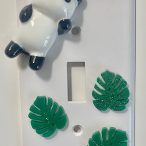 Peut inclure: Un interrupteur blanc avec un panda en céramique, deux feuilles de monstera vertes à paillettes et une feuille de monstera verte.