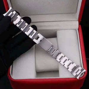 Pu&ograve; includere: Un cinturino per orologio in acciaio inossidabile color argento con un design a maglie multiple e un meccanismo di chiusura pieghevole centrale. Il cinturino in metallo ha una finitura lucida e terminali curvi per l'attacco alla cassa.