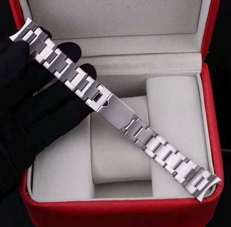 Pu&ograve; includere: Un cinturino per orologio in acciaio inossidabile color argento con un design a maglie multiple e un meccanismo di chiusura pieghevole centrale. Il cinturino in metallo ha una finitura lucida e terminali curvi per l'attacco alla cassa.