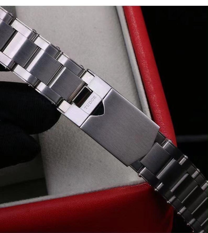 Pu&ograve; includere: Un cinturino per orologio in acciaio inossidabile color argento con finitura spazzolata e chiusura pieghevole. La chiusura &egrave; incisa con il marchio TUDOR e presenta un intaglio a forma di scudo. Le maglie sono rettangolari con bordi lucidi.