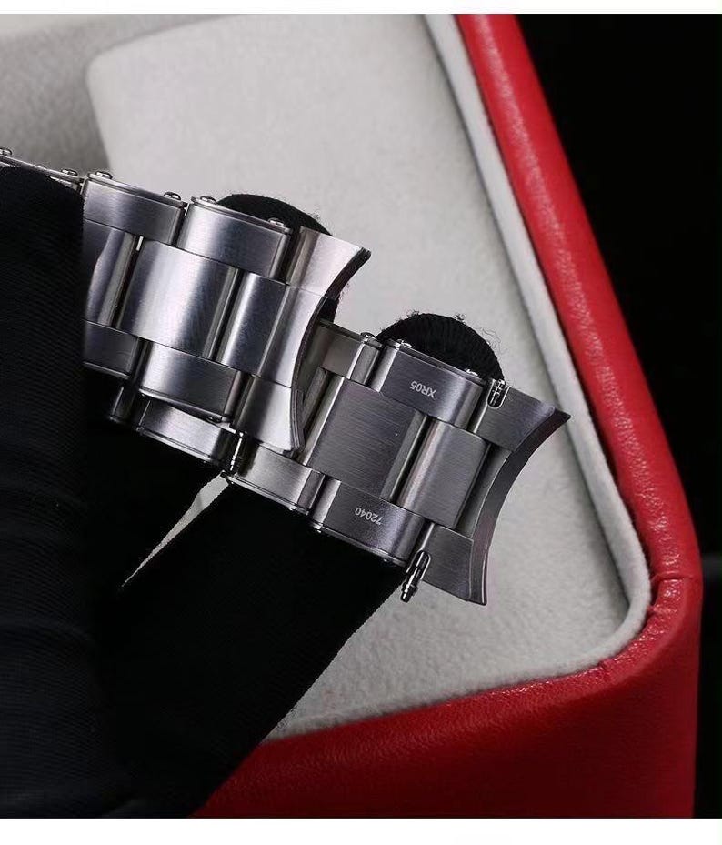 Pu&ograve; includere: Un cinturino per orologio in acciaio inossidabile color argento con finali curvi. Le maglie in metallo hanno una finitura spazzolata. Il testo XR05 e 72040 &egrave; inciso sulla superficie dei finali, che includono anche piccole barrette a molla.
