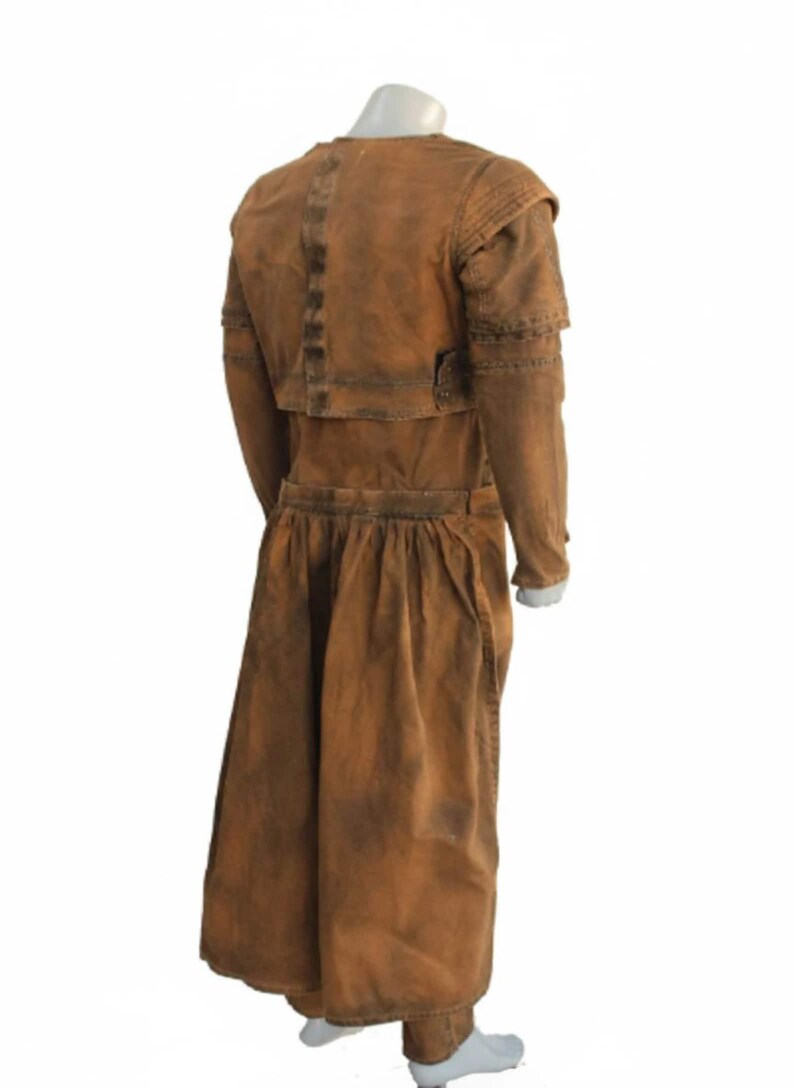 Op de afbeelding: Een bruin kostuum in vintage-stijl met een lange jas en bijpassende rok. De outfit heeft een getailleerd lijfje, lange mouwen en een geplooide rok. De stof lijkt een versleten, getextureerd materiaal te zijn, waardoor het een versleten uiterlijk heeft.