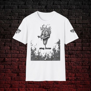 Può includere: T-shirt bianca con un disegno di testa di anatra dei cartoni animati in tonalità di grigio e nero, con fiamme e le parole "stay focus". Anche le maniche hanno un disegno a fiamma. Il disegno è stampato sul davanti.
