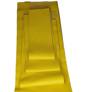 Könnte beinhalten: Ein Satz aus fünf gelben Lederblättern in verschiedenen Größen. Die Blätter sind übereinander gestapelt, wobei das größte Blatt unten und das kleinste Blatt oben liegt.