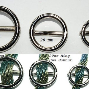 Può includere: Tre anelli in metallo argentato con una barra al centro. Gli anelli hanno un diametro di 25 mm, 20 mm e 16 mm. Gli anelli sono mostrati con un cordoncino infilato attraverso di essi.