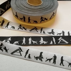 May include: Two rolls of black and white ribbon with a repeating pattern of dog agility training silhouettes. The ribbon features a dog jumping over a hurdle, a dog running with a handler, and a dog running through a tunnel.