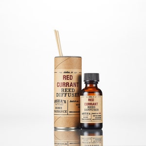 May include: A brown cardboard tube with a red currant reed diffuser inside. The tube has a label that says "dallas, tx" and "Sasha's Home Fragrance". There is a smaller bottle of red currant reed diffuser next to the tube.