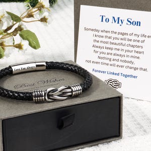 Peut inclure: Un bracelet en cuir tressé noir avec un nœud central en métal argenté et un fermoir gravé du texte Love You Always. Il est présenté avec une carte portant le texte To My Son et un poème sur le fait d'être liés pour toujours ensemble.