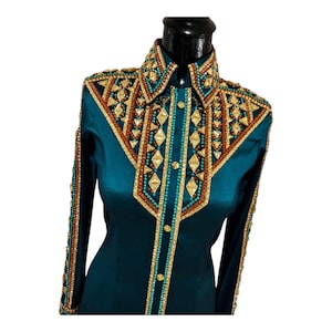 May include: A teal long-sleeve shirt featuring a structured collar and a front panel adorned with intricate gold, copper, and turquoise beadwork. The design includes geometric diamond-shaped crystals and metallic accents along the shoulders and sleeves.