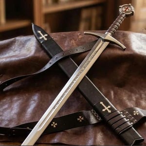 Peut inclure: Une épée en métal argenté avec une poignée gainée de cuir marron et un pommeau circulaire orné d'une croix rouge. La lame porte une inscription latine gravée. Elle est accompagnée d'un fourreau en cuir noir et d'une ceinture assortie à croix.