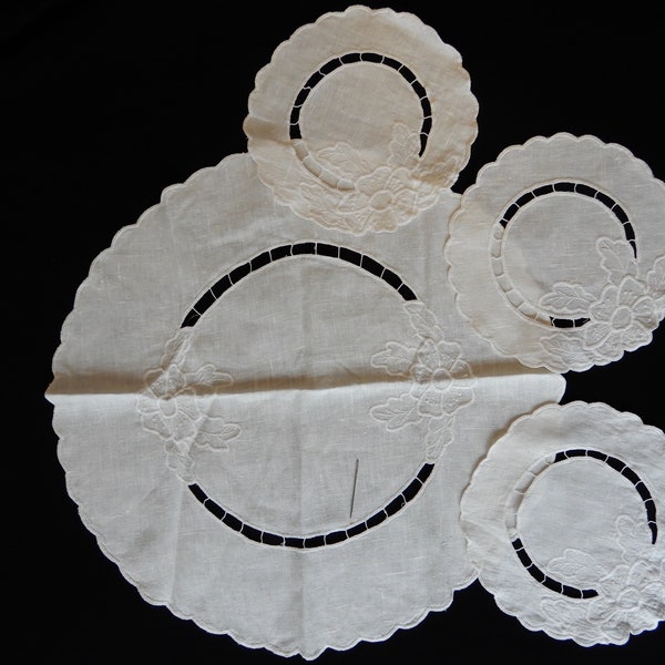 Get a Round Tuit, four round doilies with scalloped edges, cutwork, and white embroidery on eggshell white linen, three 9", one 20" diameter