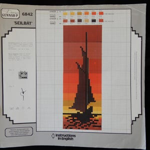 May include: A cross-stitch pattern for a sailboat at sunset. The pattern is in black, brown, orange, yellow, and red. The pattern is on a white background with a grid.