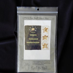 May include: A pattern for an 11" x 11" hooked rug depicting a Christmas tree with stars. The pattern is titled "#3145 Yule Rug I Peace Tree" and is part of a series of six that can be attached together to form a 22" x 33" Christmas rug. The pattern is from Heart to Hand.