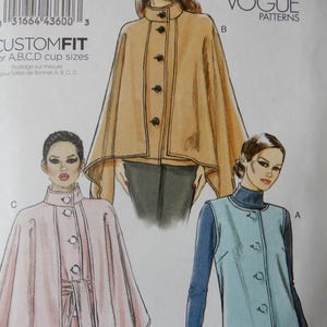 May include: Vogue Patterns sewing pattern featuring three different cape and vest designs. The pattern includes a tan cape with black buttons, a pink cape with a belt, and a light blue vest with a dark blue turtleneck.