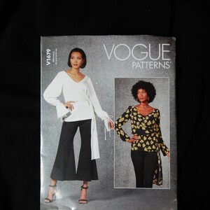 May include: Vogue Patterns sewing pattern for a white blouse with long sleeves and a black pair of trousers with a wide leg. The pattern is for size 16-18.
