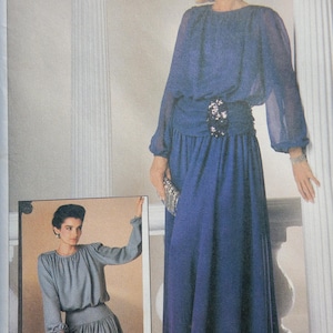 May include: A vintage fashion advertisement featuring a woman in a long, flowing blue dress with long sleeves and a cinched waist. The dress has a decorative belt. A smaller image shows a woman in a gray dress. The text "Connoisseur Collection" is at the top.