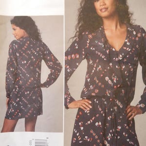 May include: A navy blue romper with a floral pattern, featuring long sleeves and a drawstring waist. The image also displays the text "REBECCA TAYLOR" and "VOGUE PATTERNS AMERICAN DESIGNER". The pattern number is V1226.