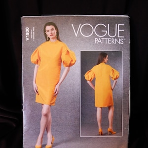May include: Vogue Patterns sewing pattern for a yellow dress with puffed sleeves. The pattern number is V1800.