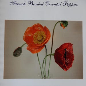 May include: A book cover titled French Beaded Oriental Poppies by Donna DeAngelis Dickt. The cover features a photograph of three beaded poppy flowers in orange and red with green stems and buds, arranged in a clear glass vase.