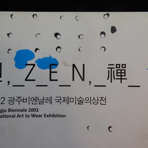 May include: A white poster with black text and blue paint splotches. The text reads "선, ZEN, 禪" and "2002 Gwangju Biennale International Art to Wear Exhibition."