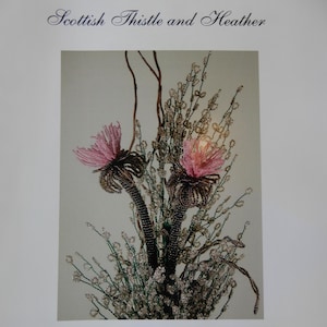 May include: A book cover titled French Beaded Scottish Thistle and Heather by Donna DeAngelis Dickt. The cover features a photograph of two pink beaded thistle flowers with dark brown beaded stems and surrounding sprigs of white beaded heather.