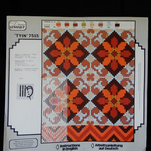 May include: Cross stitch pattern chart with instructions in English and German. The chart features a geometric design with orange, brown, and white colors. The pattern is titled 'TYIN' 7515.