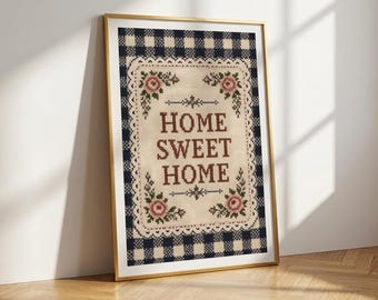 May include: A framed cross-stitch embroidery featuring the text HOME SWEET HOME in brown letters, surrounded by a decorative border of pink roses and green leaves, set against a cream background with a navy blue and white gingham outer frame.